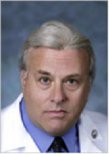 A man with grey hair wearing a white lab coat.